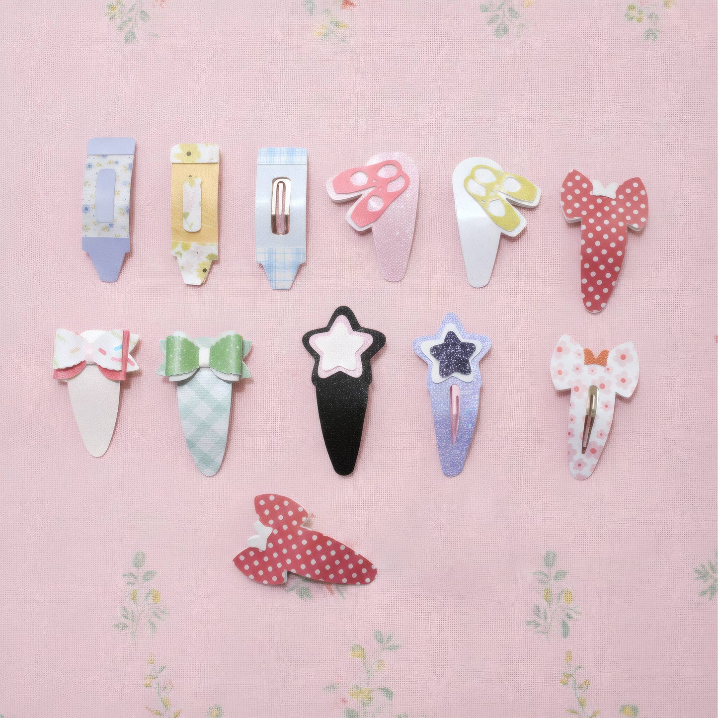 A set of ten cute, whimsical hair clips arranged on a light pink floral background. The clips feature various shapes including a tube, a mushroom, a bow, a star, and polka-dot patterns in pastel and bright colors.