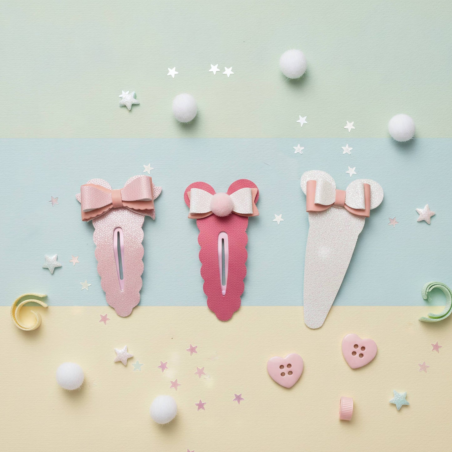 Three pastel hair claw clips arranged on a pastel striped background with stars, pom-poms, and small decorative accessories. The clips are pink, coral pink, and off-white, each with a bow detail at the top.