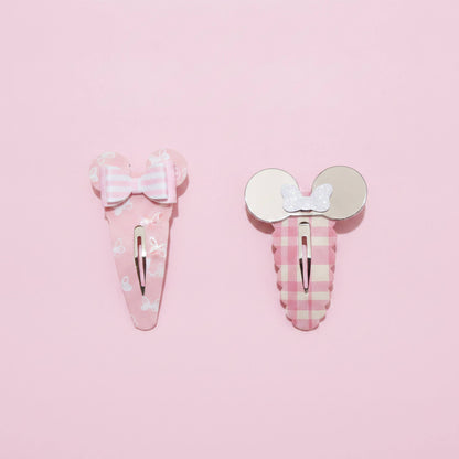 Two pink hair clips on a solid pink background. One clip features a Mouse inspired bow on a pink and white striped background with small white bunny prints.