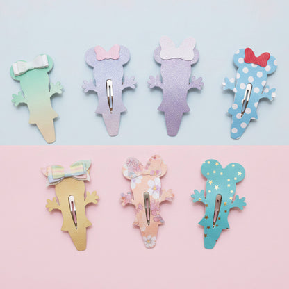 Six mouse -shaped hair clips arranged in two rows on a split pastel background. The top row is on a light blue background and the bottom row is on a light pink background.