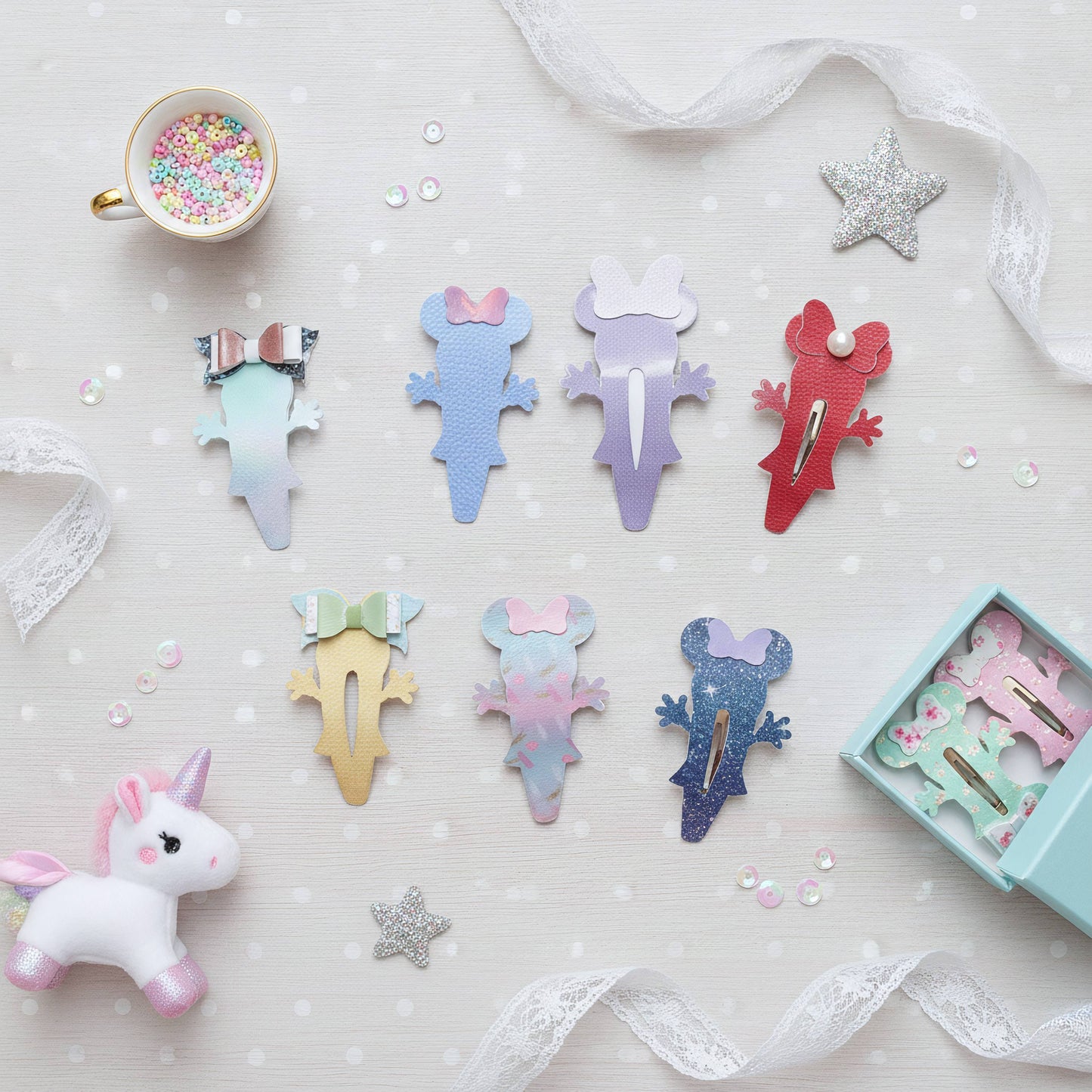 A styled flat-lay of pastel mouse-shaped hair clips arranged on a white polka-dot surface with lace ribbon, a cup of confetti, a small unicorn toy, and an open box of matching clips. The clips come in multiple pastel colors including blue, purple, red, yellow, pink, and glitter finishes.