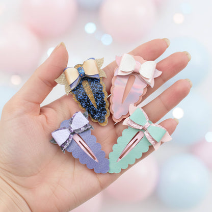 Four pastel ballet-clip hair accessories with bow details are held in a person's hand against a soft pink bokeh background.