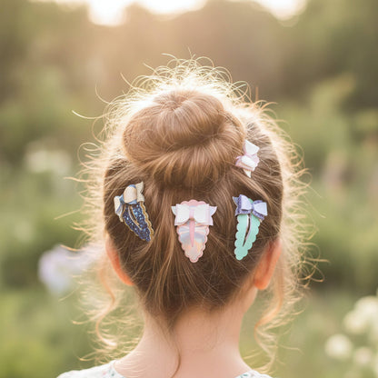 Three pastel-colored hair clips styled in a messy bun on a girl's head, photographed from behind in a sunlit outdoor setting with a soft, blurred green background.