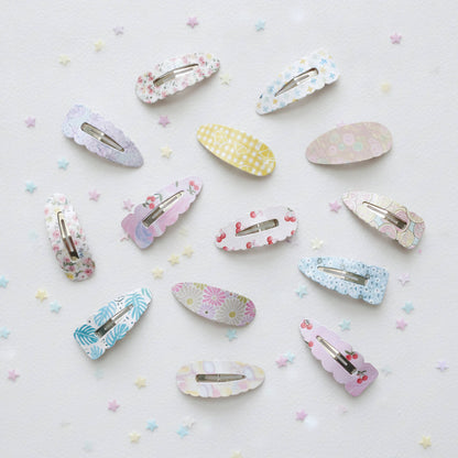 A set of 15 pastel hair claw clips with various floral, geometric, and patterned designs, arranged on a white background with scattered pastel star confetti.