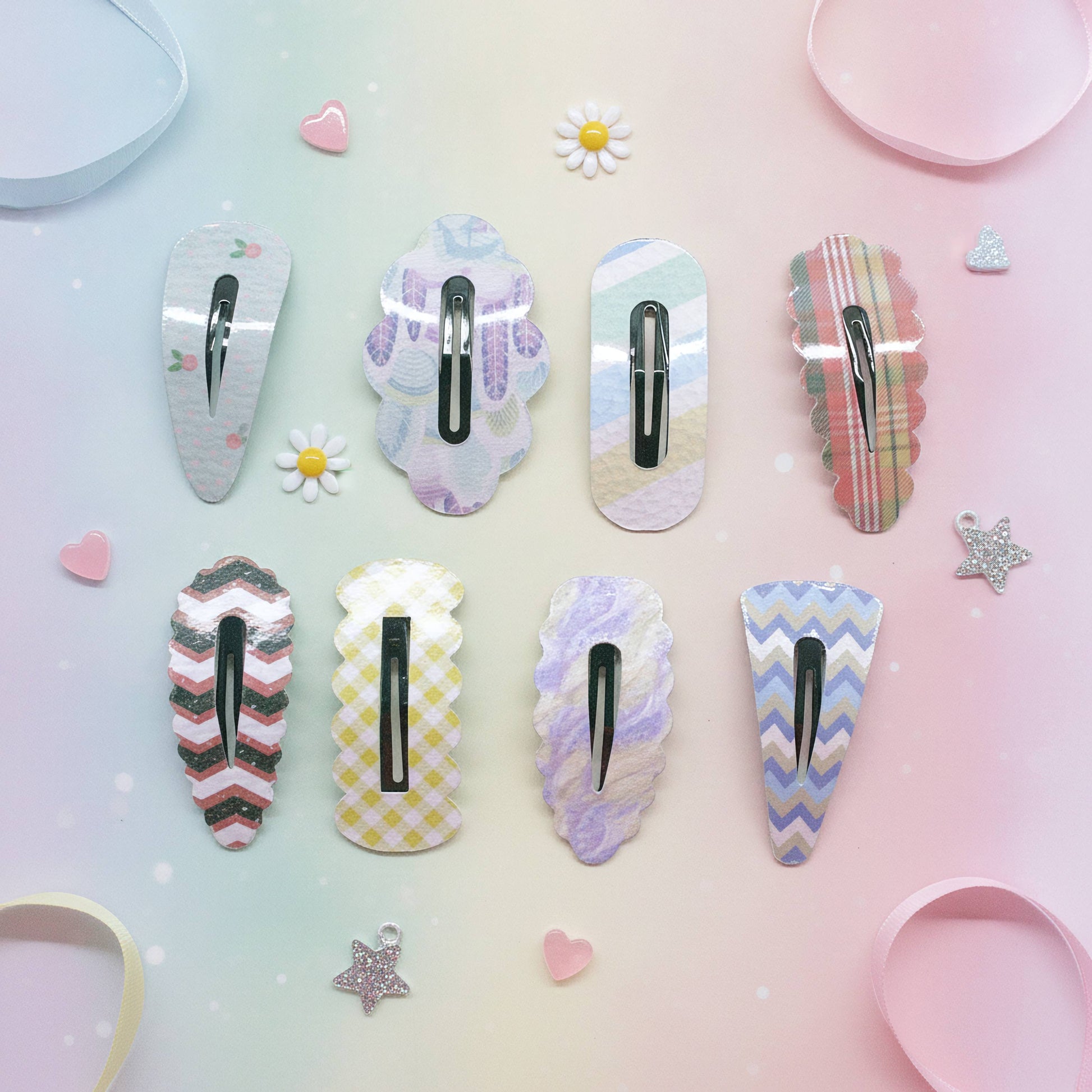 Nine decorative hair claw clips arranged in two rows on a pastel gradient background with small flower and heart props. The clips feature various pastel patterns including plaid, chevron, gingham, and marble in soft colors like pink, purple, blue, yellow, and green.