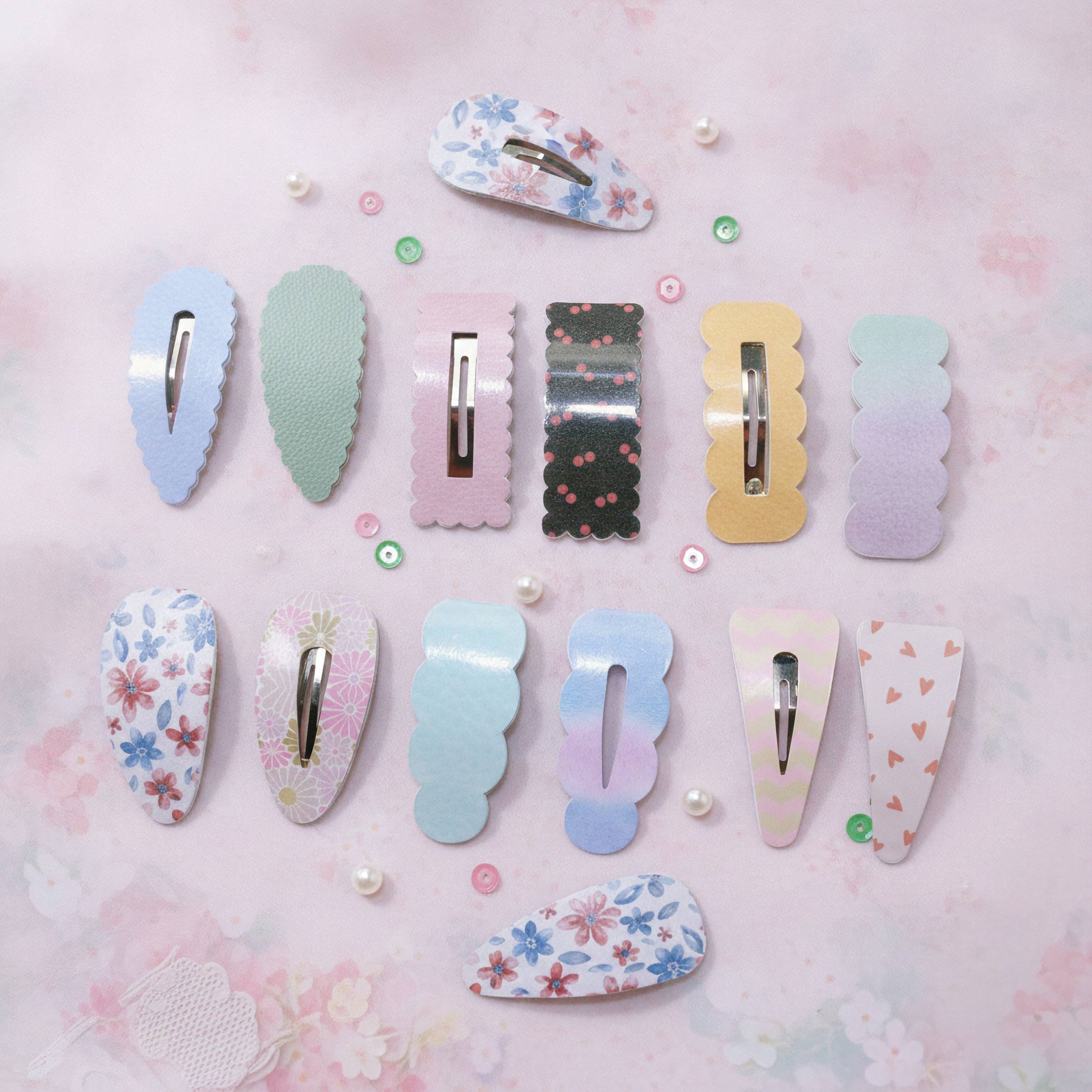 A set of pastel hair claw clips arranged on a pink floral background. The clips feature various patterns including floral prints, solid colors, stripes, and gradients in shades of blue, pink, green, yellow, and purple.