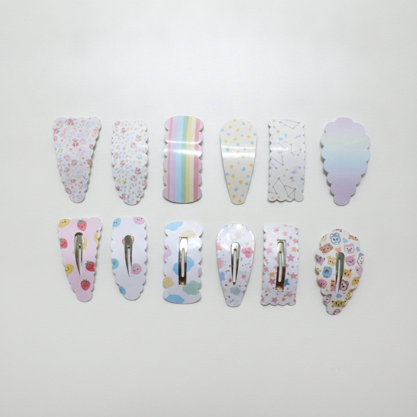 Ten pastel-colored hair claw clips arranged in two rows on a plain white background, each featuring a different cute pattern like florals, stars, rainbows, or pastel gradients.
