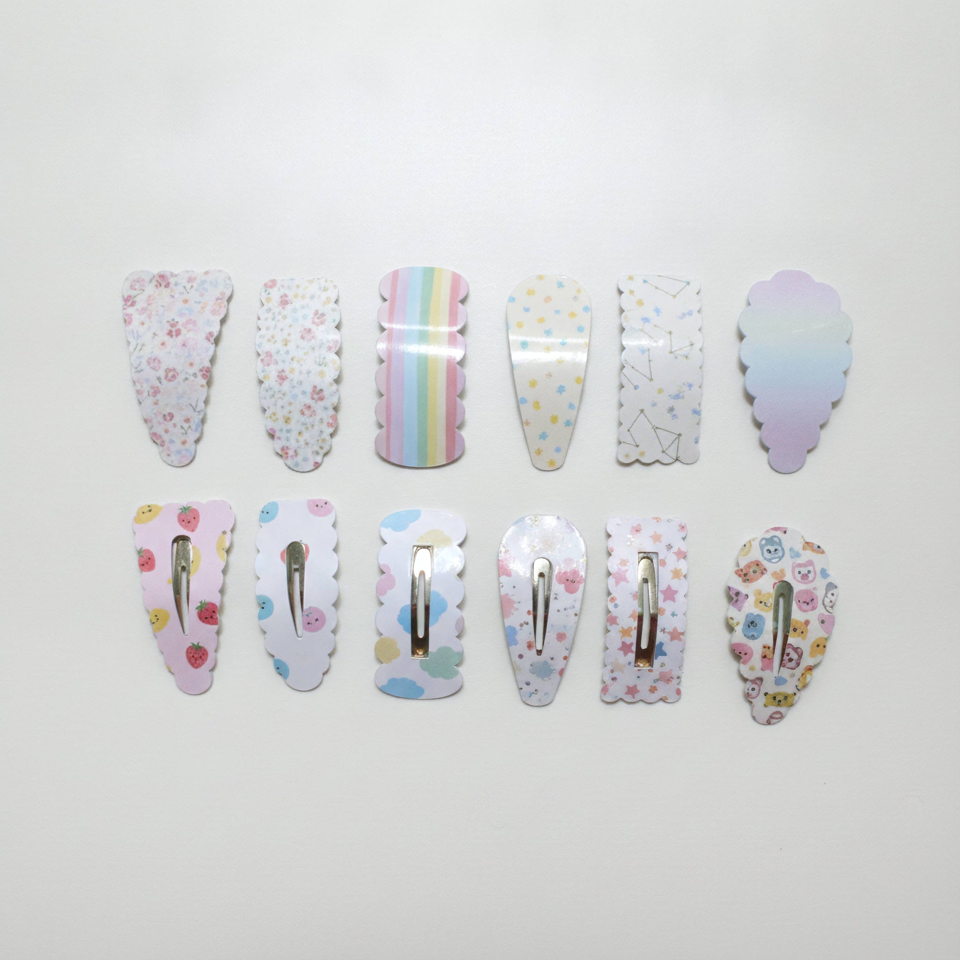 Ten pastel-colored hair claw clips arranged in two rows on a plain white background, each featuring a different cute pattern like florals, stars, rainbows, or pastel gradients.