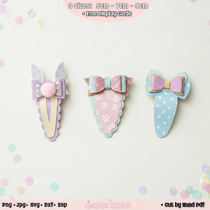 Three pastel BUNNY butterfly-shaped hair clips displayed on a light background with decorative confetti dots. The clips feature glittery bows, patterned wings, and pom-poms in soft pink, lavender, and light blue.