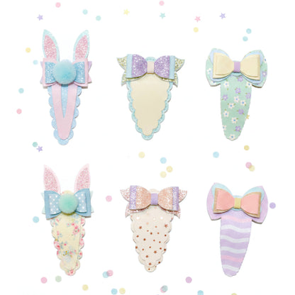 Six pastel bunny-themed hair clips arranged on a white background with scattered confetti dots. The clips feature pastel colors, glitter textures, bows, floral prints, polka dots, and striped patterns.