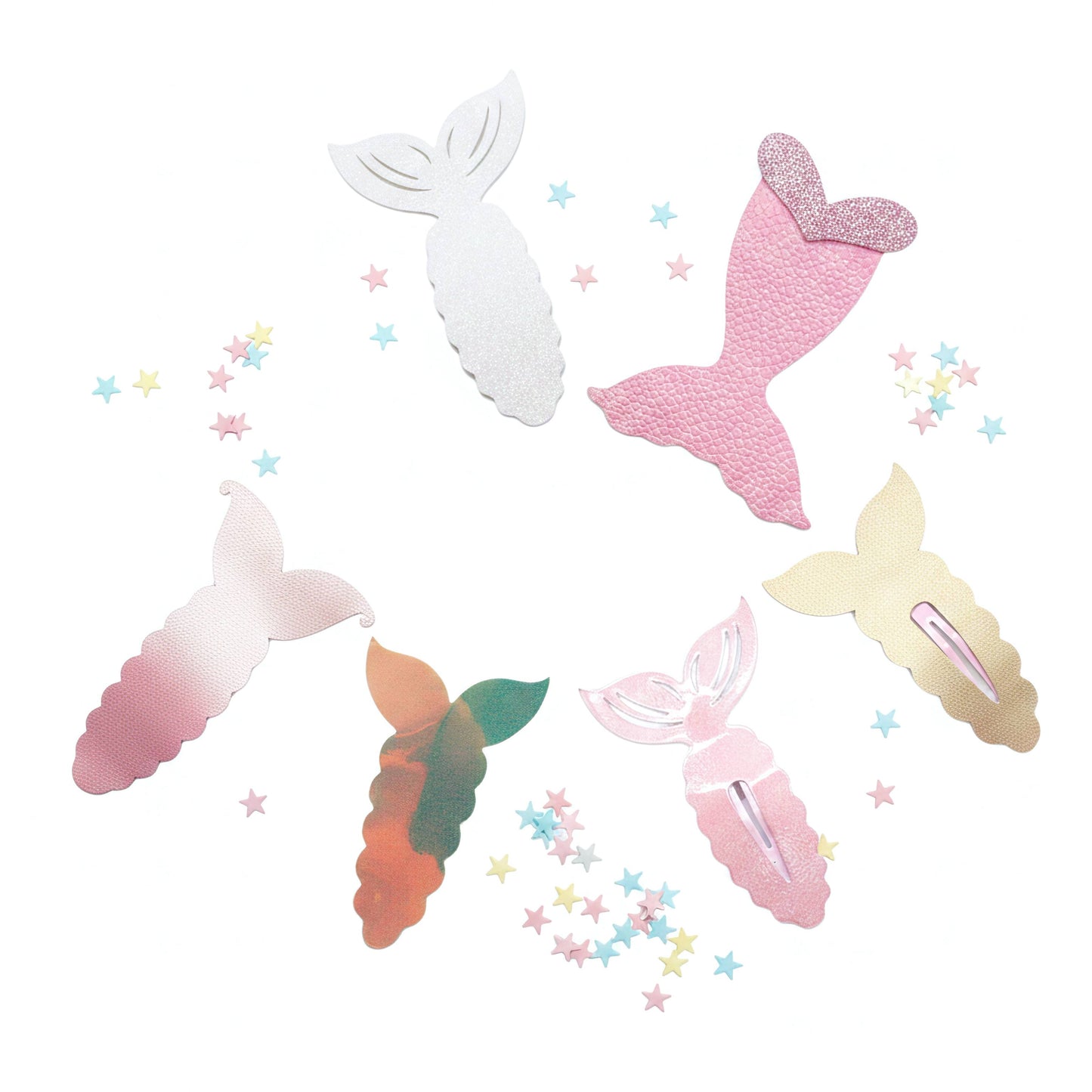 Six mermaid tail hair clips in various designs including textured pink, glittery gold, ombre pink, gradient green-orange, and solid white, arranged on a white background with scattered pastel star confetti.