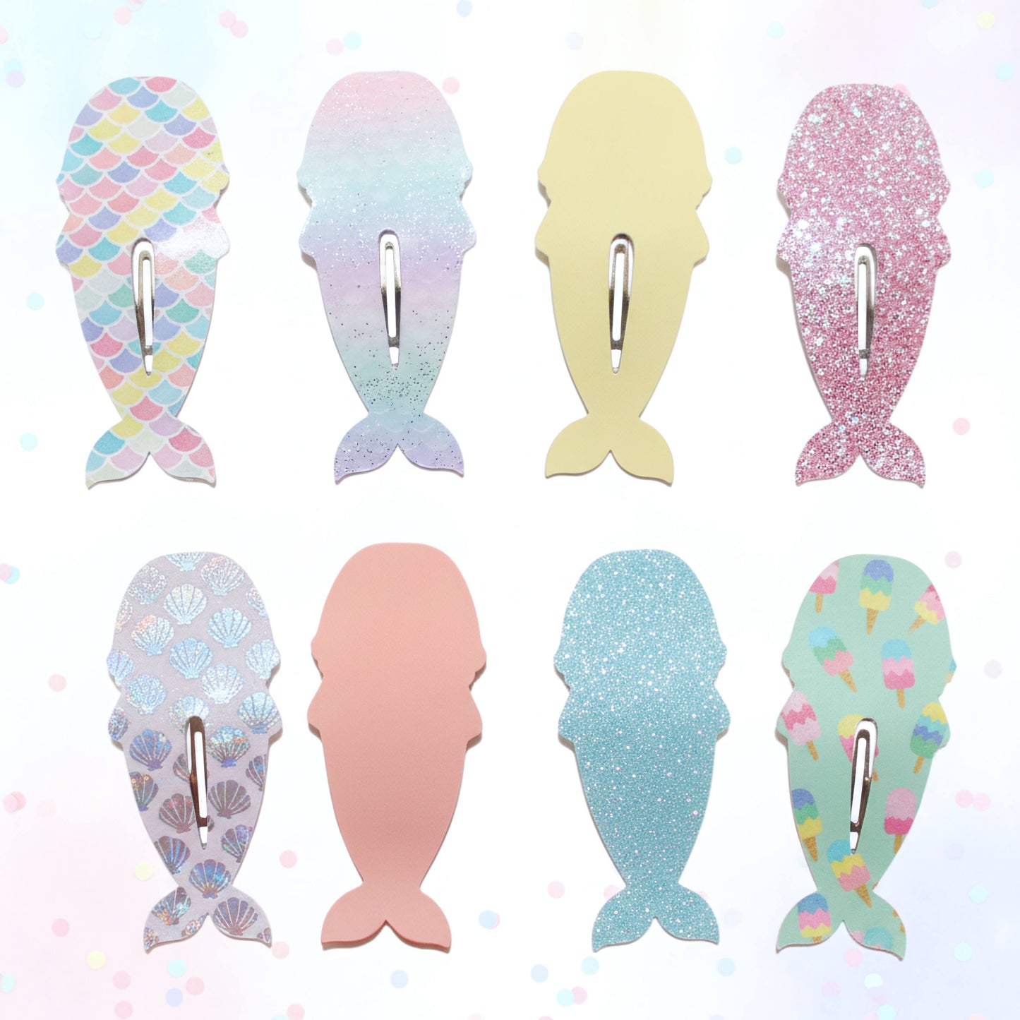 Eight mermaid tail-shaped hair clips arranged in a 2x4 grid on a light pastel background. The clips feature different designs: scales, iridescent gradient, solid pale yellow, glitter pink, scallop pattern, solid pale pink, glitter light blue, and ice cream print.