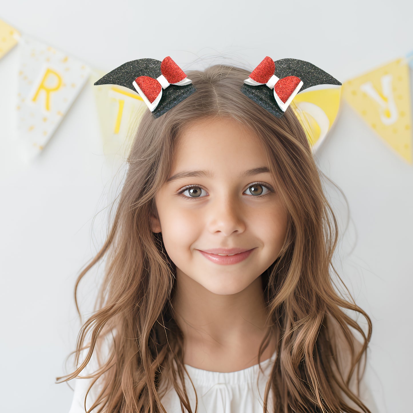 Young girl wearing a headband with cat ears and red bows, smiling at the camera.