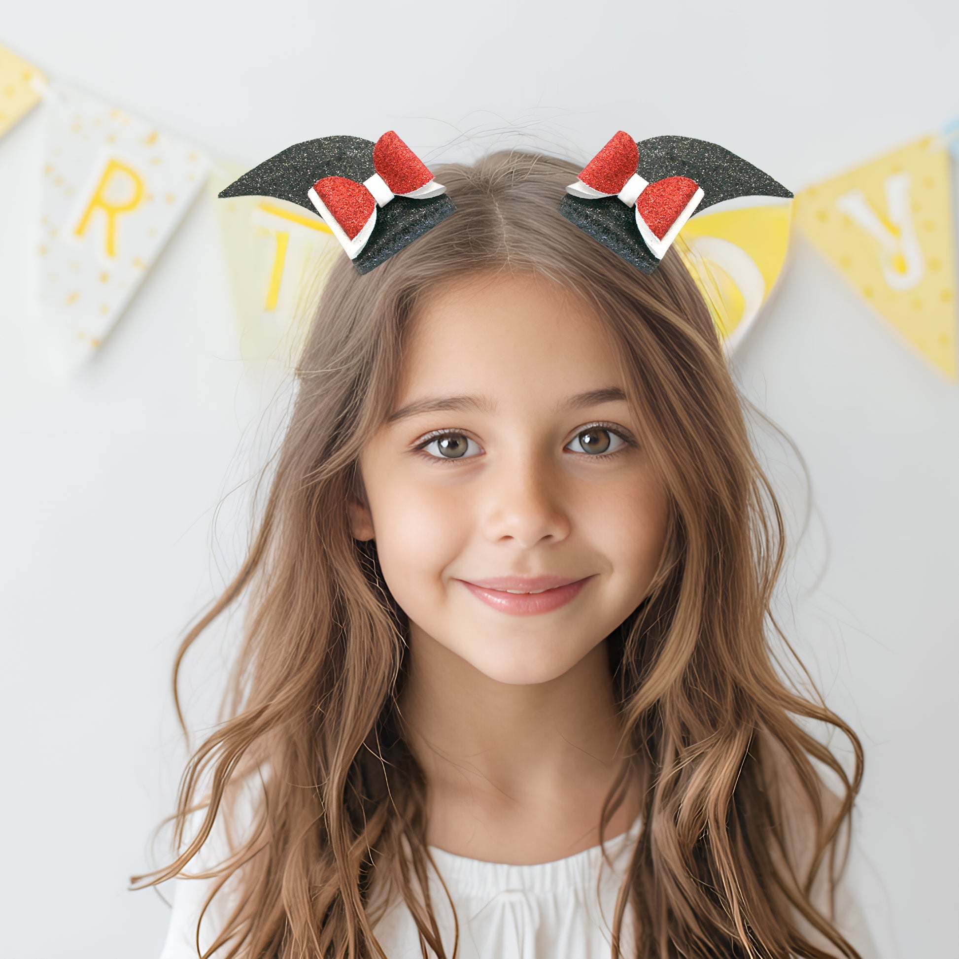 Young girl wearing a headband with cat ears and red bows, smiling at the camera.