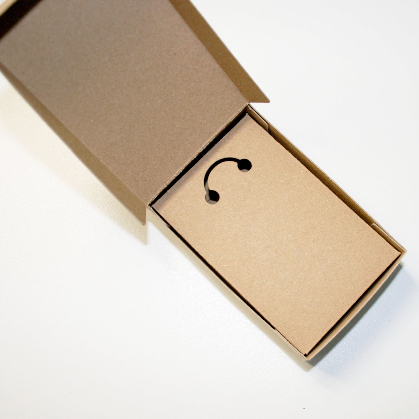 Open cardboard box with a black hook on a white background