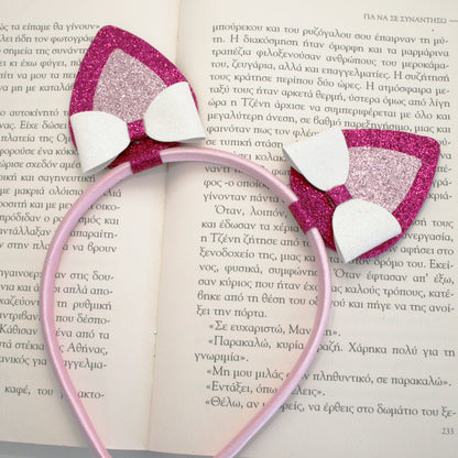 Photograph of a pink headband with glittery pink and white cat ears and a pink glittery butterfly clip, featuring a small pink plush bunny.